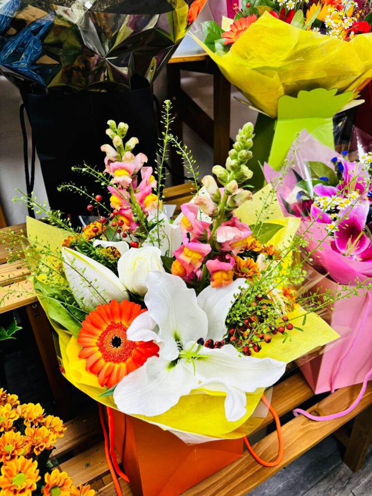 Floral arrangement with deep red roses and golden autumn blooms